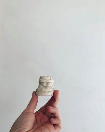 Picture of a small coil pot, made by Kayla Noble at age 4,  held agains a white backdrop. 